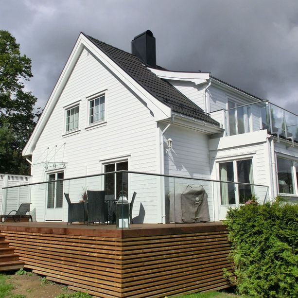 Hvitt eldre hus med fasade arbeid utført, balkong, glass rekkverk